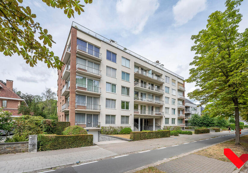 Residentie Woodside is gelegen op de Kardinaal Mercierlaan, volledig omgeven door groen.  Het appartement is gelegen op de vierde verdieping en omvat ruime inkomhal met ingebouwde vestiaire,  volledig geïnstalleerde keuken (vaatwas, frigo met diepvries, 